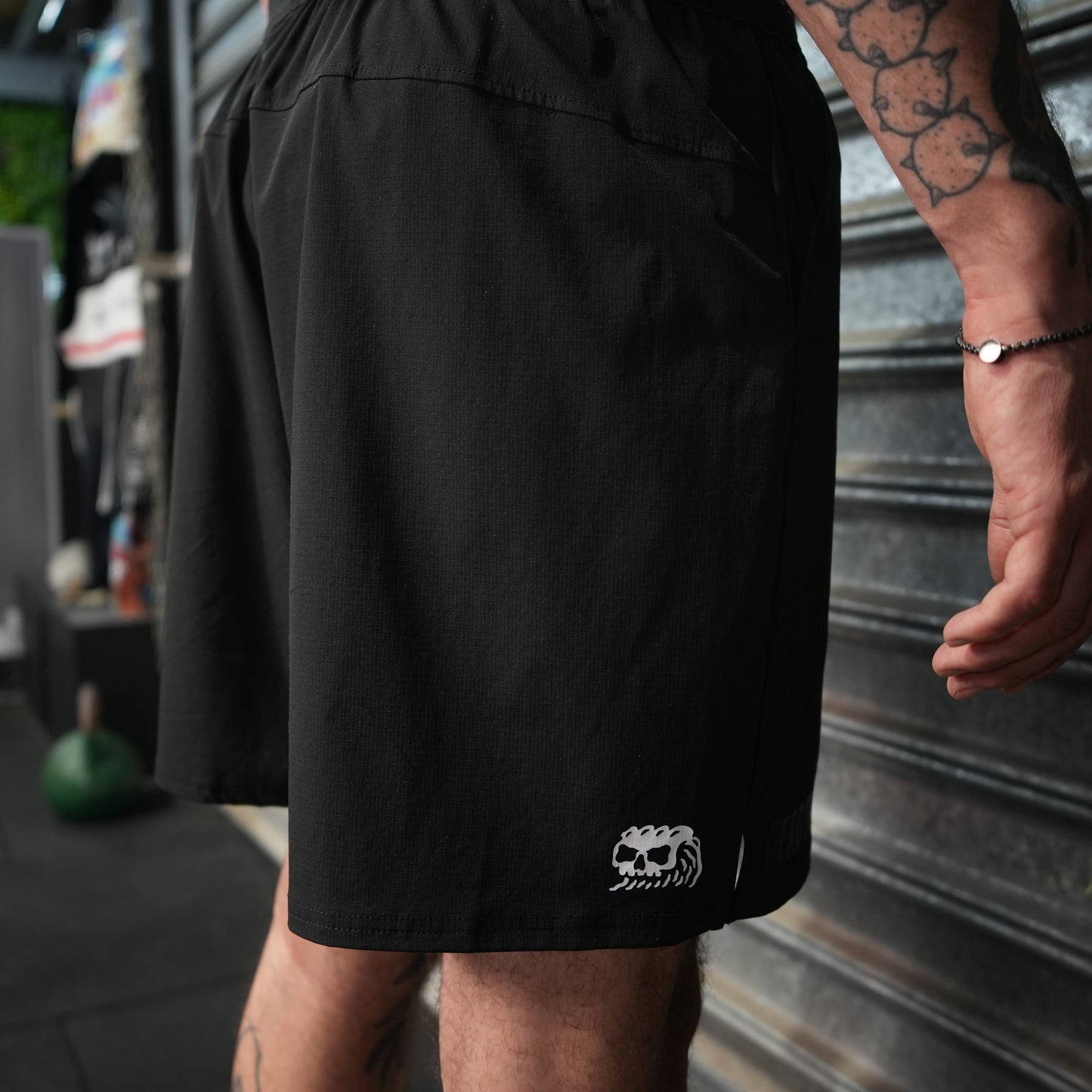 Person wearing black shorts with a Dead Tide logo on a blurred background