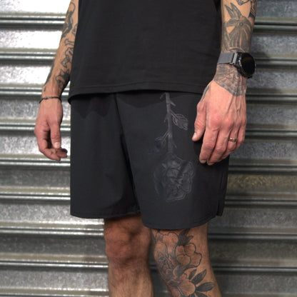 Person wearing black shorts with a rose design against a metallic background