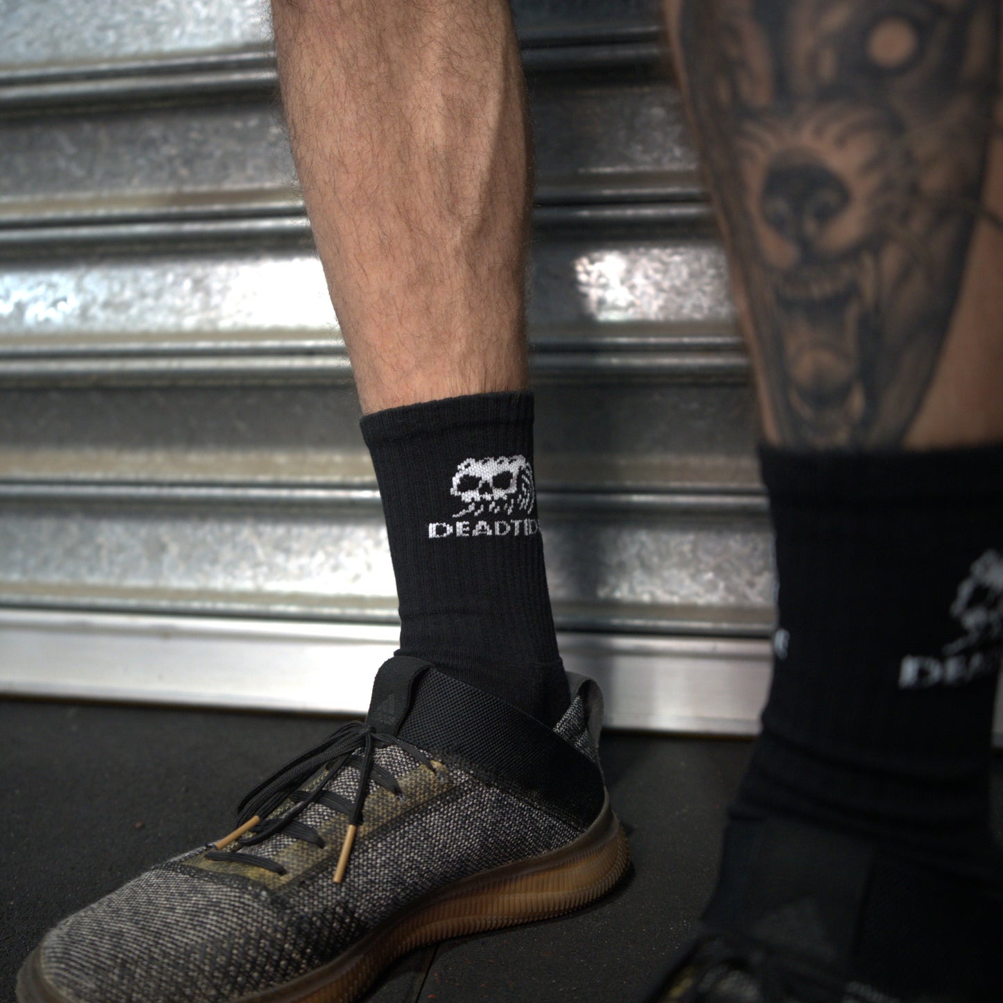 Person wearing black socks with Dead Tide logo.